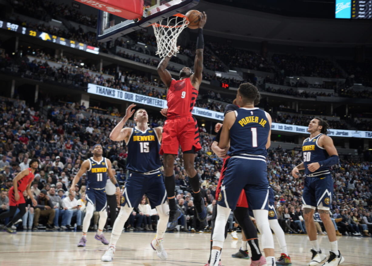 Portland Trail Blazers forward Jerami Grant, center, drives the lane between Denver Nuggets center Nikola Jokic, left, and forward Michael Porter Jr. in the first half of an NBA basketball game Tuesday, Jan. 17, 2023, in Denver.