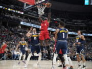 Portland Trail Blazers forward Jerami Grant, center, drives the lane between Denver Nuggets center Nikola Jokic, left, and forward Michael Porter Jr. in the first half of an NBA basketball game Tuesday, Jan. 17, 2023, in Denver.