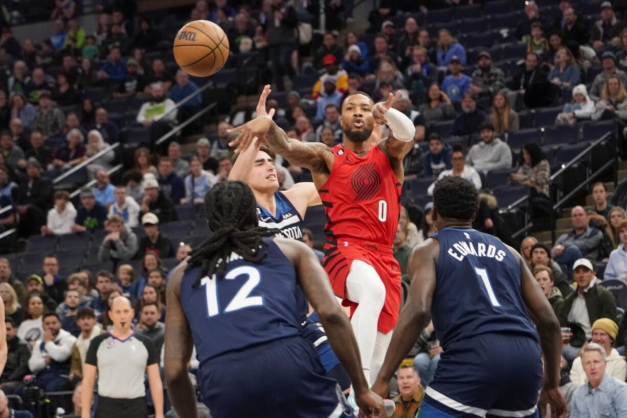 Portland Trail Blazers guard Damian Lillard (0) makes a pass over Minnesota Timberwolves center Luka Garza, second from left, forward Taurean Prince (12) and guard Anthony Edwards (1) during the first half of an NBA basketball game, Wednesday, Jan. 4, 2023, in Minneapolis.