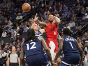 Portland Trail Blazers guard Damian Lillard (0) makes a pass over Minnesota Timberwolves center Luka Garza, second from left, forward Taurean Prince (12) and guard Anthony Edwards (1) during the first half of an NBA basketball game, Wednesday, Jan. 4, 2023, in Minneapolis.