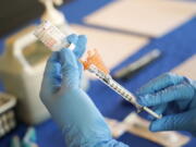 FILE - A nurse prepares a syringe of a COVID-19 vaccine at an inoculation station in Jackson, Miss., July 19, 2022. U.S. health officials are proposing a simplified approach to COVID-19 vaccinations, which would allow most adults and children to get a once-a-year shot to protect against the mutating virus. The new system unveiled Monday, Jan. 23, 2023 would make COVID-19 inoculations more like the annual flu shot. Americans would no longer have to keep track of how many shots they've received or how many months it's been since their last booster. (AP Photo/Rogelio V.