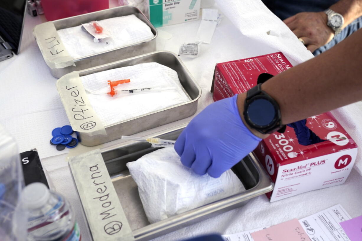 Syringes with vaccines are prepared at the L.A. Care and Blue Shield of California Promise Health Plans' Community Resource Center where they were offering members and the public free flu and COVID-19 vaccines Friday, Oct. 28, 2022, in Lynwood, Calif. The U.S. is poised to make COVID-19 vaccinations more like a yearly flu shot, a major shift in strategy despite a long list of questions about how to best protect against a still rapidly mutating virus.