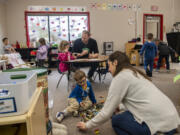 Transitional kindergarten teacher Shawn Sears, back right, asks student Claire Lindelien, back left, to draw a letter while paraeducator Lauren Rhew, front right, arranges dinosaur toys for student Valen Neufeld on Tuesday during class at Hockinson Heights Elementary School. Transitional kindergarten programs provide a year of pre-K style learning for students who missed the age cutoff for kindergarten and have limited access to early learning options.