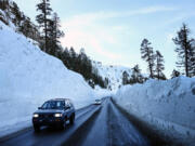 Vehicles pass along a highway snowplowed through deep snow after a series of atmospheric river storms on Jan. 21, 2023, near Kirkwood, California.