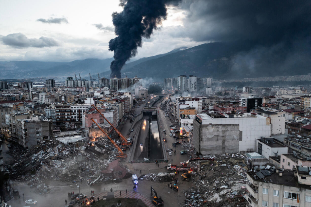 Smoke billows from the Iskenderun Port as rescue workers work at the scene of a collapsed building on Tuesday in Iskenderun, Turkey. An earthquake hit near Gaziantep, Turkey, in the early hours of Monday, and was followed by another 7.5-magnitude tremor. The quakes caused widespread destruction in southern Turkey and northern Syria and were felt in nearby countries.