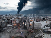 Smoke billows from the Iskenderun Port as rescue workers work at the scene of a collapsed building on Tuesday in Iskenderun, Turkey. An earthquake hit near Gaziantep, Turkey, in the early hours of Monday, and was followed by another 7.5-magnitude tremor. The quakes caused widespread destruction in southern Turkey and northern Syria and were felt in nearby countries.