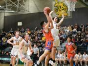 Enumclaw's Karson Holt (21) contests a shot attempt from Ridgefield's Carter Thompson in a Class 2A state opening round game on Saturday, Feb. 25, 2023, at Auburn High School.