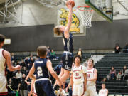 Seattle Christian players look on as Seton Catholic's Jack Jenniges elevates for a two-handed dunk during a Class 1A state opening round game on Friday, Feb. 24, 2023, at Auburn High School.