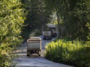 Trucks drive toward the Zimmerly gravel pit east of Washougal in July 2018. Operators of the pit, long the subject of opposition from neighbors and conservation groups, are seeking permission to keep extracting gravel from the site.