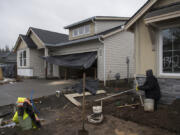 Jose Ponce of Tapias Landscaping, right, works in the front yard of a home under construction in the Parkers Abby development in Vancouver.