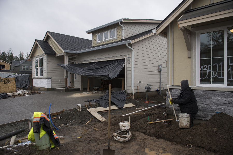 Jose Ponce of Tapias Landscaping, right, works in the front yard of a home under construction in the Parkers Abby development in Vancouver.