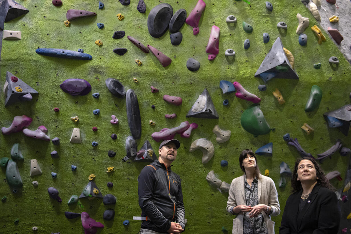 From left: Hanz Kroesen, co-owner of Source Climbing Center, looks up at the climbing wall with U.S. Rep. Marie Gluesenkamp Perez, D-Skamania, and Isabel Guzman, head of the Small Business Administration, during a tour Friday morning.