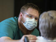 Certified nursing assistant Benjamin Nikolaychuk shares eye contact and a reassuring touch with a resident at The Hampton at Salmon Creek Memory Care Community, using techniques from a new approach to memory care called Humanitude.