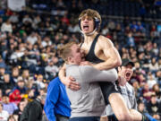 Skyview’s JJ Schoenlein, 170 pounds, leaps into his coach’s arms after winning the championship at Mat Classic XXXIV on Saturday, February 18, 2023, at the Tacoma Dome.