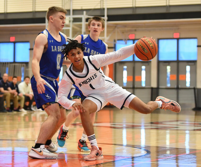 King’s Way junior Jaydon Hall, center, makes a move around La Salle senior Gabriel Craig, left,  on Saturday, Feb. 25, 2023, during the Knights’ 59-44 win against La Salle at Battle Ground High School.