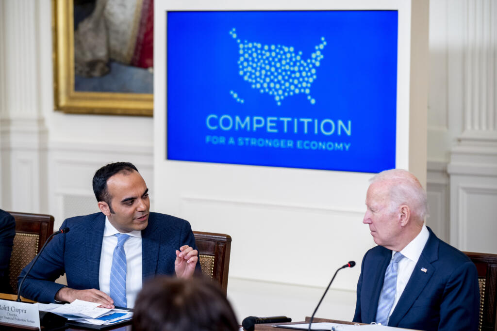 Consumer Financial Protection Bureau director Rohit Chopra, left, accompanied by President Joe Biden, right, speaks at a meeting with his Competition Council on the economy and prices in the East Room of the White House in Washington, Wednesday, Feb. 1, 2023.