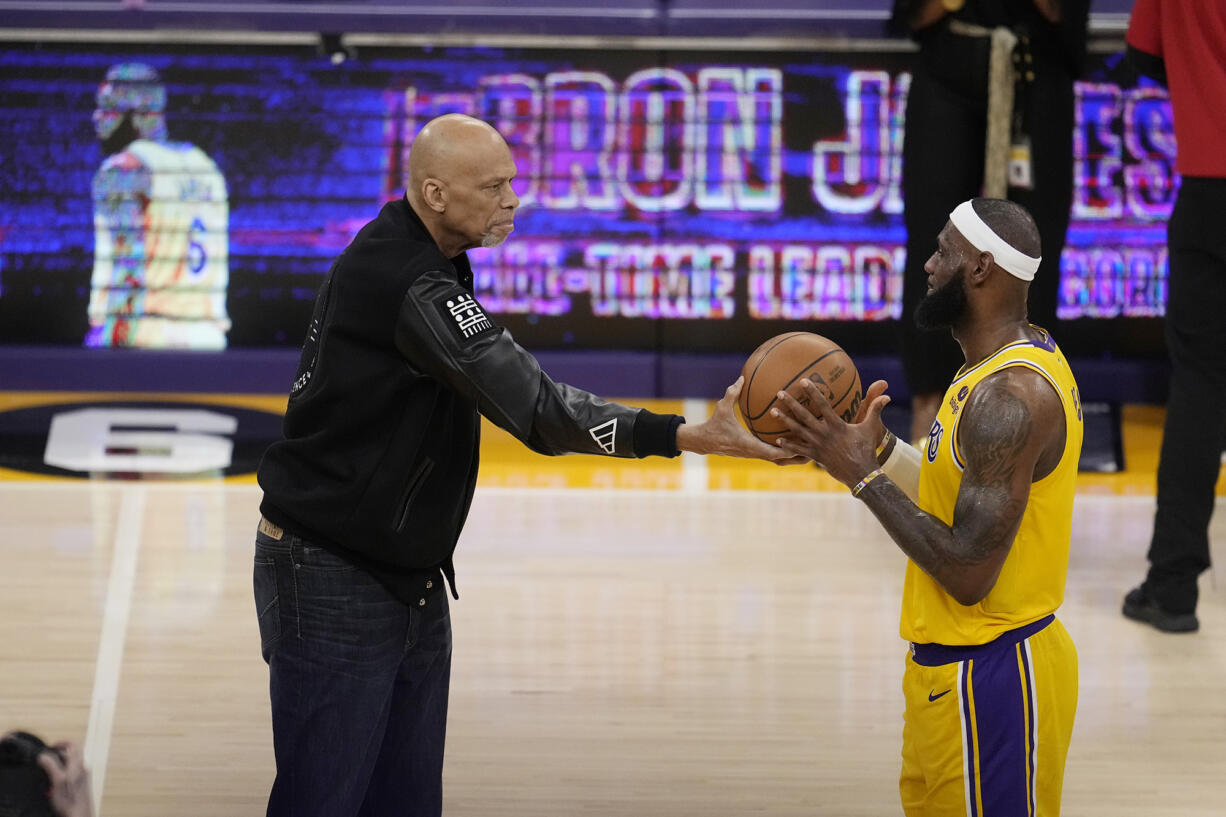 Kareem Abdul-Jabbar, left, hands the ball to Los Angeles Lakers forward LeBron James after passing Abdul-Jabbar to become the NBA's all-time leading scorer during the second half of an NBA basketball game against the Oklahoma City Thunder Tuesday, Feb. 7, 2023, in Los Angeles.