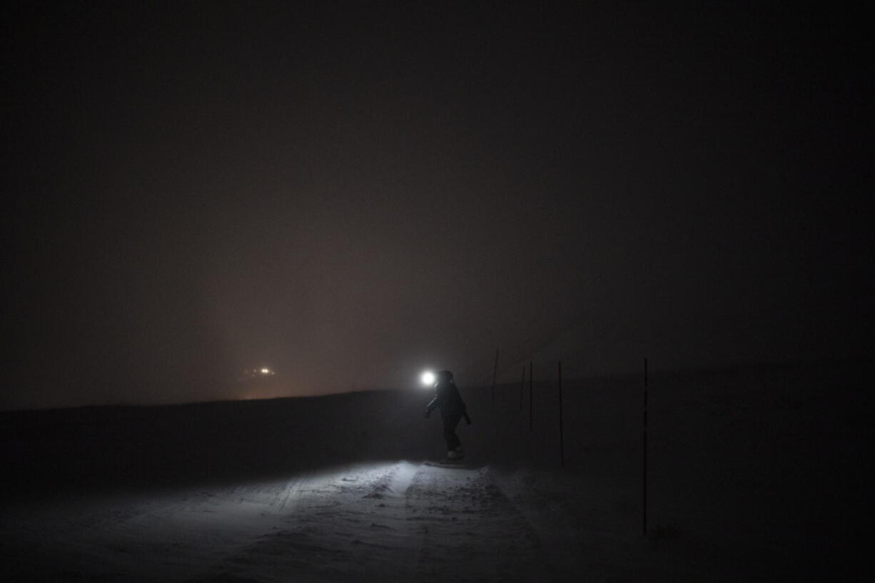 The Rev. Siv Limstrand walks with her rifle to the church's cabin in Bolterdalen, Norway, Monday, Jan. 9, 2023. For the lone pastor in this fragile, starkly beautiful environment, the challenge is to fulfill the church's historical mission of ministering to those in crisis while addressing a pressing and divisive contemporary challenge. "We pray every Sunday for everyone who's affected by climate change," Limstrand said.