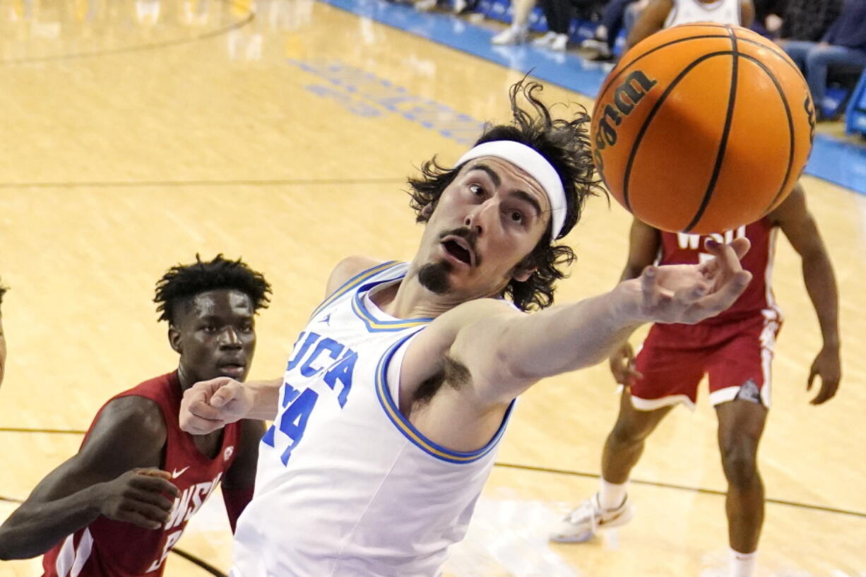 UCLA guard Jaime Jaquez Jr., right, reaches for a rebound as Washington State forward Mouhamed Gueye watches during the first half of an NCAA college basketball game Saturday, Feb. 4, 2023, in Los Angeles. (AP Photo/Mark J.