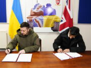 Ukrainian President Volodymyr Zelensky, left, and British Prime Minister Rishi Sunak sign a declaration of unity at a military facility in Lulworth, Dorset, England, Wednesday Feb. 8, 2023.