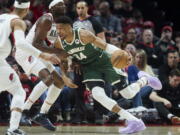 Milwaukee Bucks forward Giannis Antetokounmpo, right, drives to the basket toward Portland Trail Blazers forward Jerami Grant during the first half of an NBA basketball game in Portland, Ore., Monday, Feb. 6, 2023.