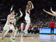 Portland Trail Blazers guard Damian Lillard, center, shoots a 3-point basket over Milwaukee Bucks guard Wesley Matthews, left, and center Brook Lopez during the first half of an NBA basketball game in Portland, Ore., Monday, Feb. 6, 2023.