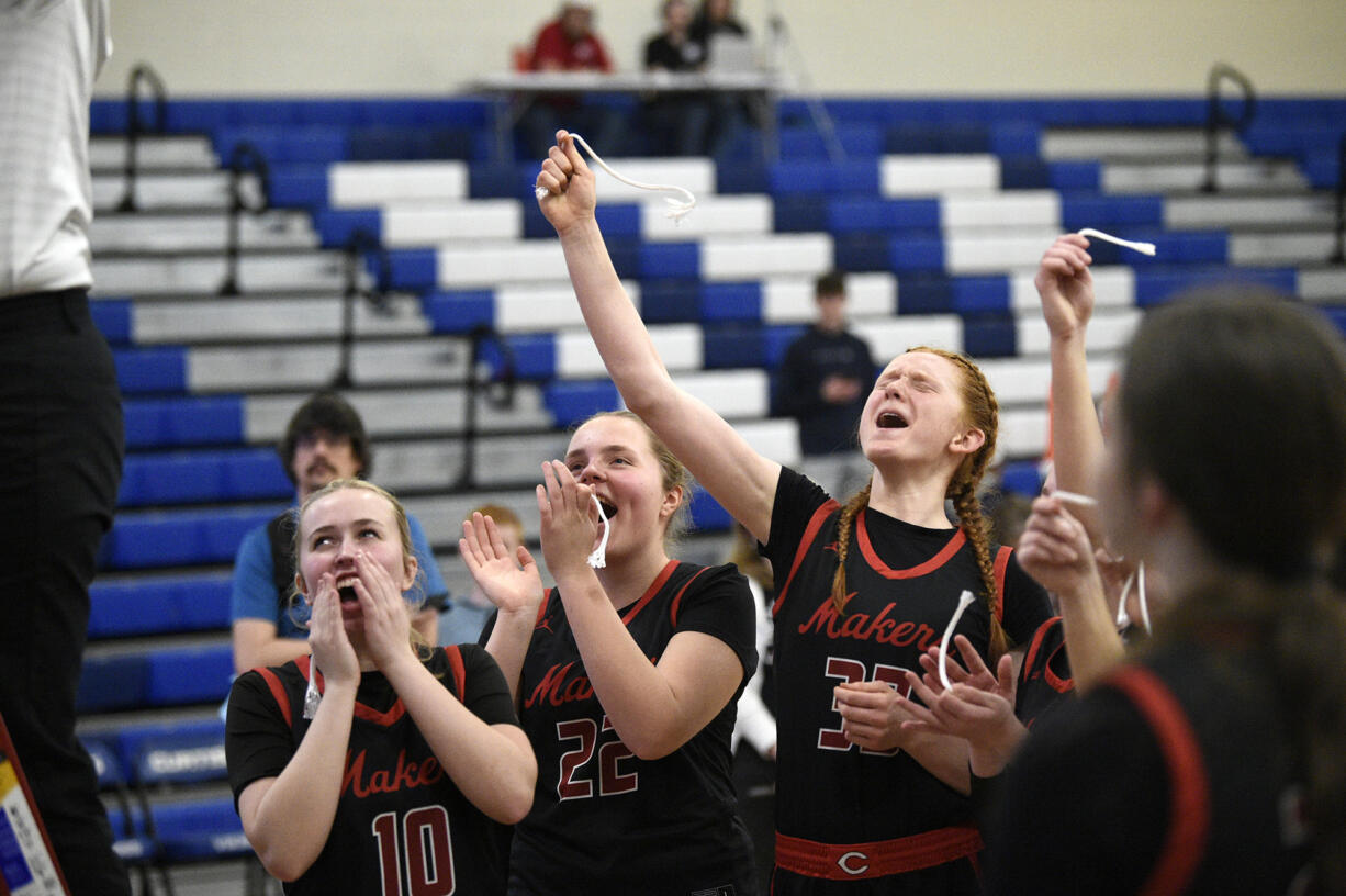 Camas' Kendall Bachelder (10), Marta Biasiolo (22) and Addison Harris cheer as assistant coach Lisa Schneider cuts the net after the Papermakers' win in the 4A bi-district girls basketball championship game at Curtis High School in University Place on Saturday, Feb. 18, 2023.