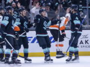 Seattle Kraken forward Yanni Gourde, center, is congratulated by defenseman Justin Schultz (4), defenseman Carson Soucy (28) and forward Eeli Tolvanen (20) after scoring a goal during the first period of an NHL hockey game against the Philadelphia Flyers, Thursday, Feb. 16, 2023, in Seattle.