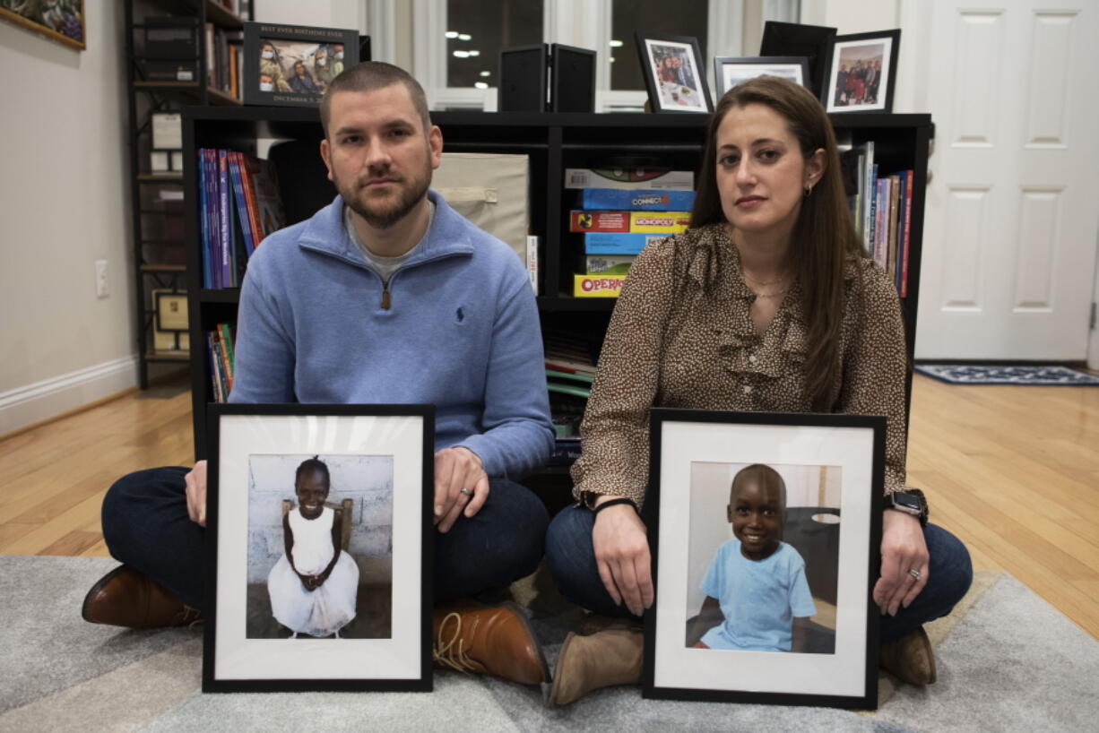 Bryan and Julie Hanlon hold photos of their adopted Haitian children, Gina, left, and Peterson, in a play area of their home in Washington, Tuesday, Feb. 7, 2023. They became the legal parents of the siblings in 2022 and fear they won't be able to secure their passports and fly them out of Haiti.