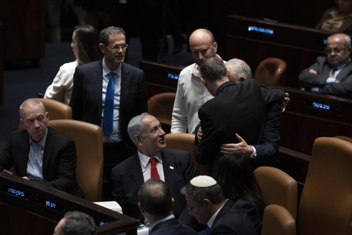 Israel's Prime Minister Benjamin Netanyahu, center, and lawmakers congratulate Justice Minister Yariv Levin, back to camera, after his speech in Israel's parliament, the Knesset, just before a vote on a contentious plan to overhaul the country's legal system, in Jerusalem, early Tuesday, Feb. 21, 2023.