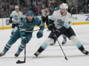 San Jose Sharks center Noah Gregor, left, reaches for the puck next to Seattle Kraken defenseman Jaycob Megna during the second period of an NHL hockey game in San Jose, Calif., Monday, Feb. 20, 2023.