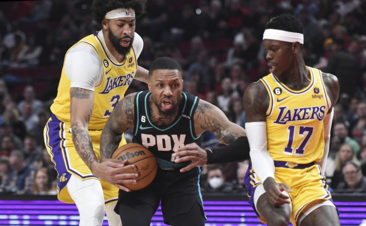 Portland Trail Blazers guard Damian Lillard, center, drives to the basket against Los Angeles Lakers forward Anthony Davis, left, and guard Dennis Schroder, right, during the first half of an NBA basketball game in Portland, Ore., Monday, Feb. 13, 2023.