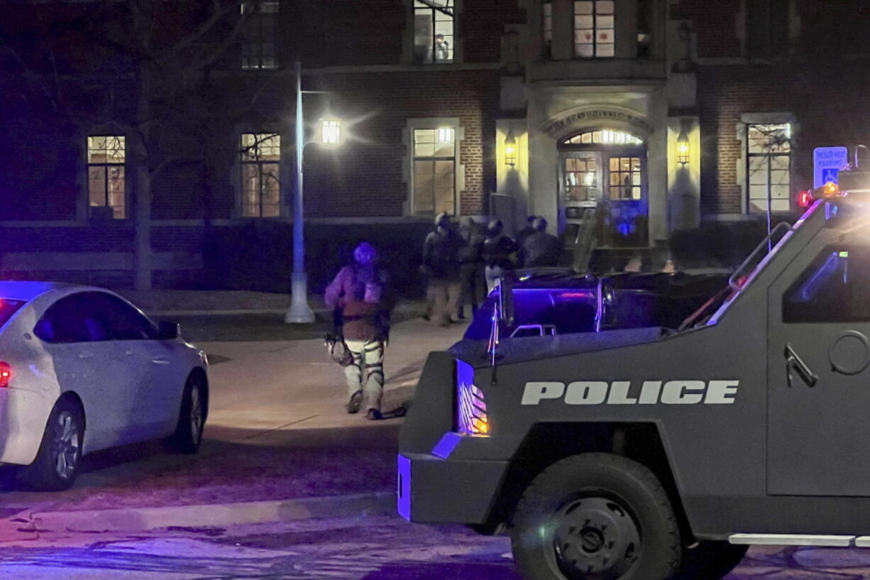 Armed police officers with weapons drawn rush into Phillips Hall on the campus of Michigan State University, in East Lansing, Mich., as authorities respond to reports of shootings, late Monday, Feb. 13, 2023.