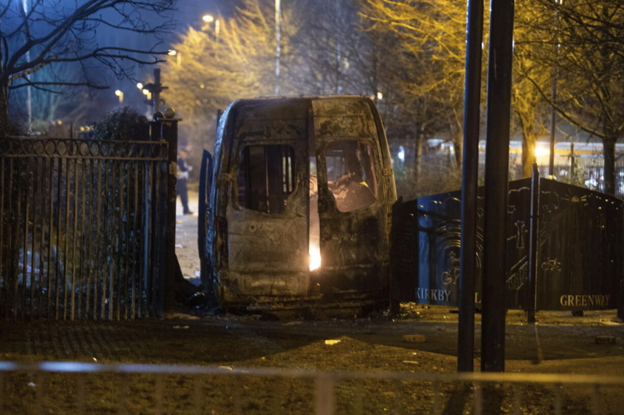 A burnt out police van after a demonstration outside the Suites Hotel in Knowsley, Merseyside, where people were protesting against asylum seekers staying at the hotel, in Knowsley, England, Friday, Feb. 10, 2023. An anti-migration protest outside a hotel housing asylum-seekers in northwest England turned violent and resulted in the arrests of 15 people, local police said. Merseyside Police department said Saturday that a police officer and two civilians sustained minor injuries during the Friday night disturbance in the village of Knowsley.