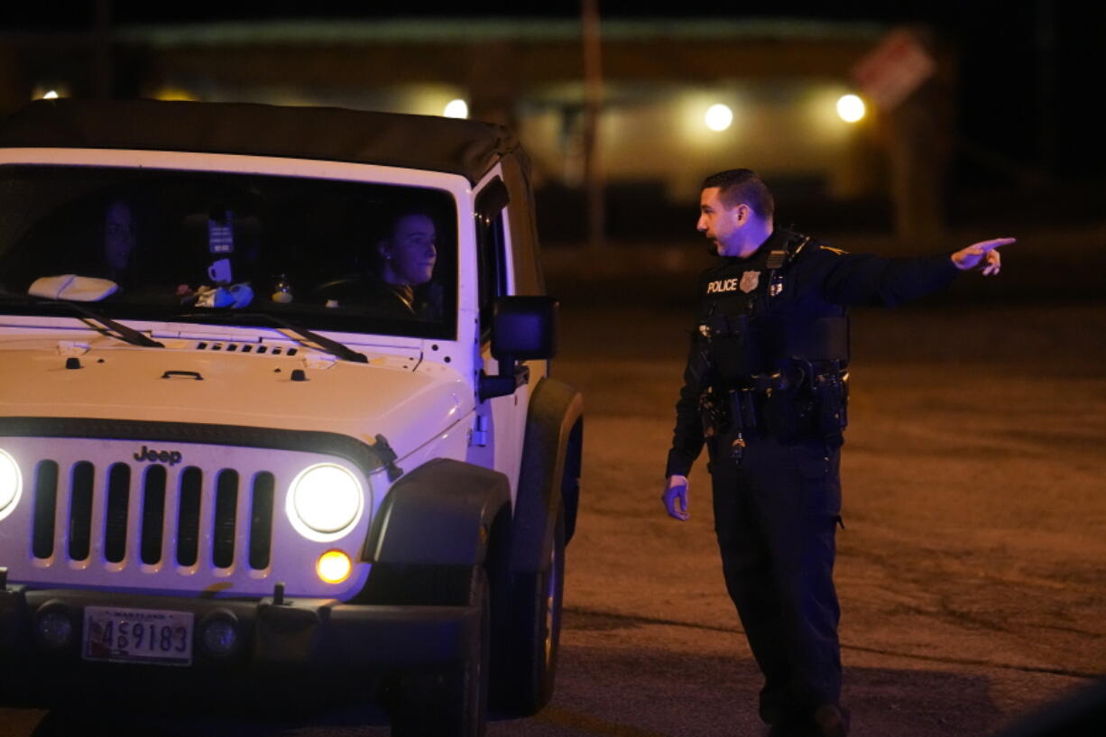 Police officers give evacuation directs to patrons leaving a bar in the area of the search for a gunman Thursday, Feb. 9, 2023, in Fallston, Md. A police officer in Maryland was seriously injured in gunfire Thursday night amid a manhunt for a suspect who had wounded a different officer after firing at police the previous afternoon, officials said.