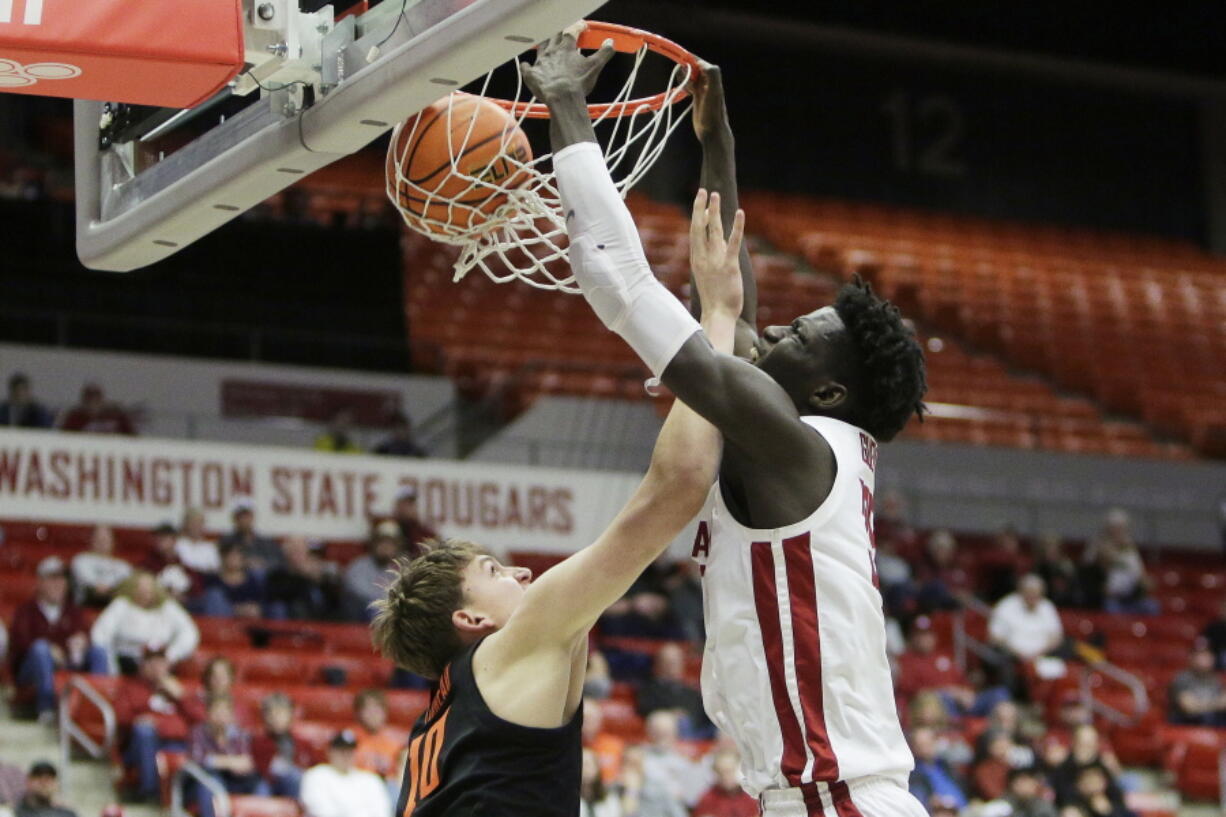 Washington State forward Mouhamed Gueye, right, dunks while defended by Oregon State forward Tyler Bilodeau during the first half of an NCAA college basketball game, Thursday, Feb. 16, 2023, in Pullman, Wash.