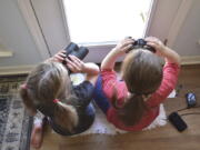 Two girls watching birds through a window with binoculars, bird lists and cameras in Elm Grove, La., during the Great Backyard Bird Count in February 2022. About 385,000 people from 192 countries took part in the 2022 count, and their results have been used by scientists to study bird populations worldwide.