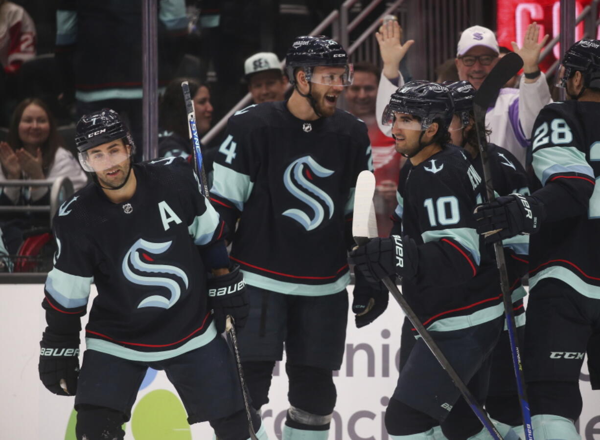 Seattle Kraken right wing Jordan Eberle (7) celebrates his second goal of the night against the Detroit Red Wings with Jamie Oleksiak (24) and Matty Beniers (10), during the second period of an NHL hockey game Saturday, Feb. 18, 2023, in Seattle.