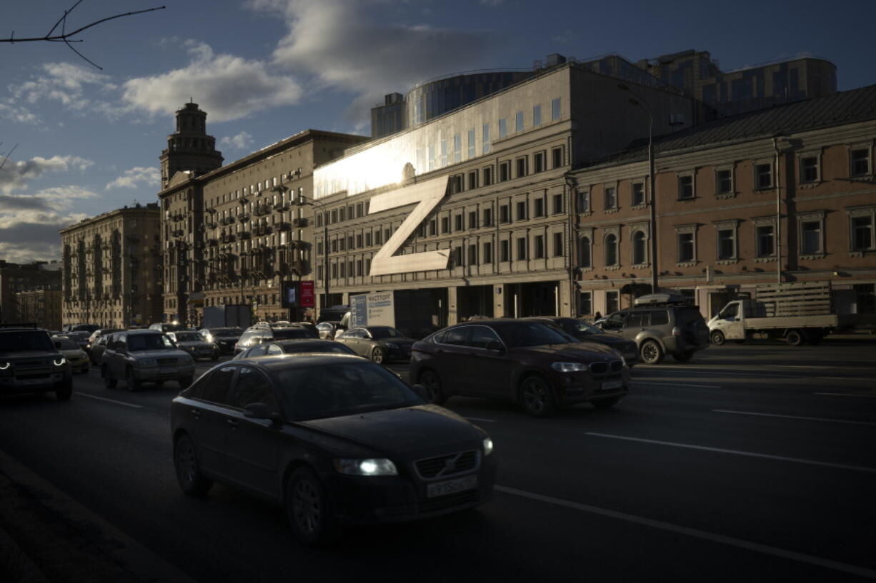 Cars in Moscow, Russia, on Wednesday, March 30, 2022, drive past a building decorated with a huge letter "Z," which has become a symbol of the Russian military operation in Ukraine, along with a hashtag reading, "We don't abandon our own." The symbols serve as reminders of the conflict that has dragged on for a year.