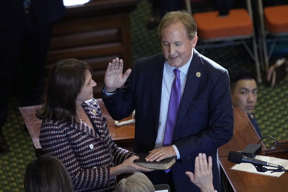 FILE - Texas Attorney General Ken Paxton, right, stands with his wife Texas state Sen. Angela Paxton, left, as he is sworn in for a third term in Austin, Texas, Tuesday, Jan. 10, 2023. Ken Paxton has agreed to apologize and pay $3.3 million in taxpayer money to four former staffers who accused him of corruption in 2020, igniting an ongoing FBI investigation of the three-term Republican. Under terms of a preliminary lawsuit settlement filed Friday, Feb. 10, 2023, Paxton made no admission of wrongdoing to accusations of bribery and abuse of office, which he has denied for years and called politically motivated.