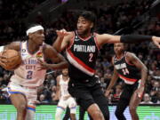 Oklahoma City Thunder guard Shai Gilgeous-Alexander, left, drives to the basket on Portland Trail Blazers forward Trendon Watford (2) during the first half of an NBA basketball game in Portland, Ore., Friday, Feb. 10, 2023.