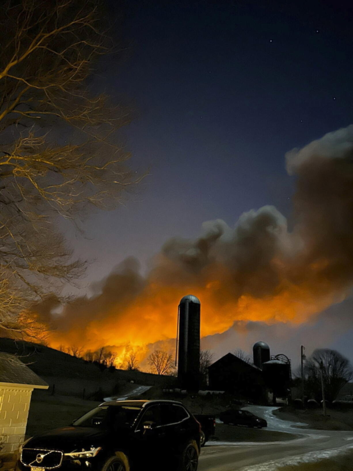 In this photo provided by Melissa Smith, a train fire is seen from her farm in East Palestine, Ohio, Friday, Feb. 3, 2023. A train derailment and resulting large fire prompted an evacuation order in the Ohio village near the Pennsylvania state line on Friday night, covering the area in billows of smoke lit orange by the flames below.