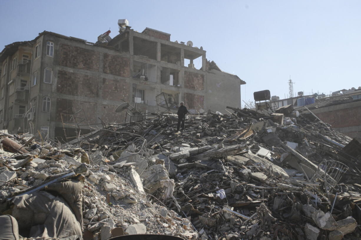 A man walks among the debris of collapsed buildings Thursday in Hatay, southern Turkey. The catastrophic earthquake last week killed more than 22,000 and left at least 5.3 million people homeless.