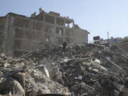 A man walks among the debris of collapsed buildings Thursday in Hatay, southern Turkey. The catastrophic earthquake last week killed more than 22,000 and left at least 5.3 million people homeless.