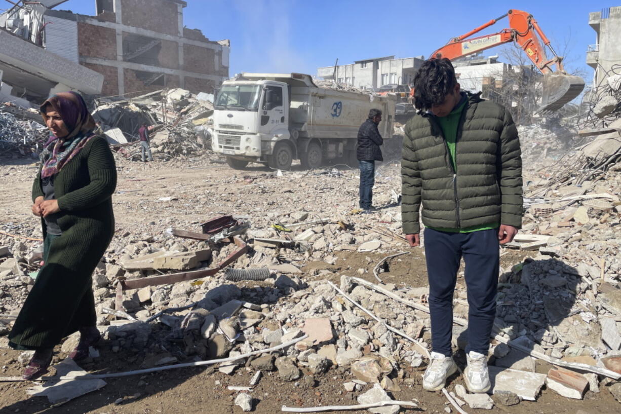 Taha Erdem, 17, right, his mother Zeliha Erdem, left, and father Ali Erdem stand next to the debris from a building where Tahan was trapped after the earthquake of Feb. 6, in Adiyaman, Turkey, Friday, Feb. 17, 2023. Taha Erdem, a resident of southeastern Turkey's Adiyaman, is one of the hundreds of survivors pulled out of collapsed buildings after the Feb. 6 powerful quake. Erdem, who is 17, filmed himself on his phone while stuck and sandwiched between concrete in what he thought would be his last words.