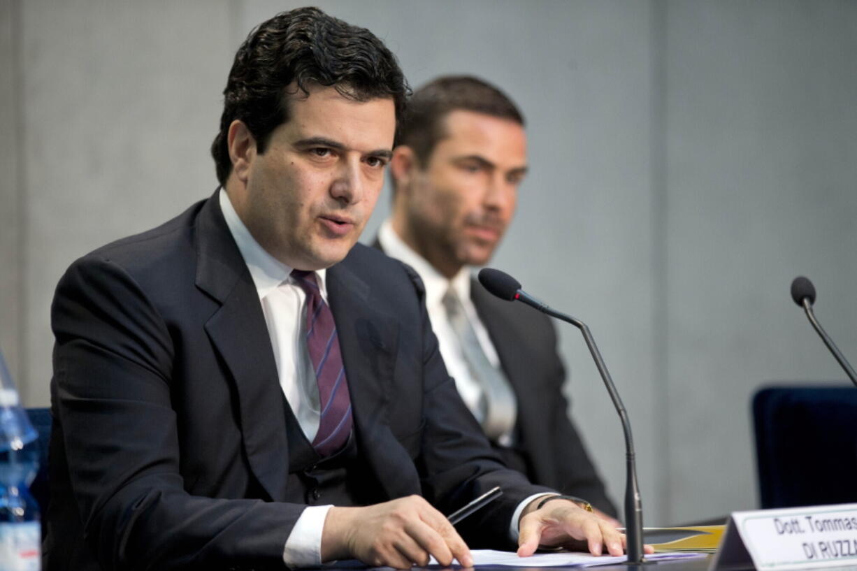 FILE -- In this April 28, 2016 file photo, Tommaso Di Ruzza, then director of the Vatican Financial Information Authority, left, flanked by Rene Brulhart, then president of the AIF. An Italian journalist on Wednesday deflated an accusation in the Vatican's sprawling financial trial, as he disputed Vatican prosecutors' claims about the source of a document concerning the Vatican's 350 million euro investment in a London property. Prosecutors had accused Di Ruzza of having given the journalist a copy of a contract related to the London deal, alleging a violation of Vatican confidentiality laws.