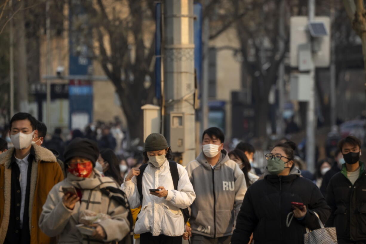 Commuters wearing face masks walk along a street during the morning rush hour in the central business district in Beijing, Thursday, Feb. 16, 2023.