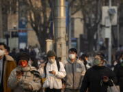 Commuters wearing face masks walk along a street during the morning rush hour in the central business district in Beijing, Thursday, Feb. 16, 2023.