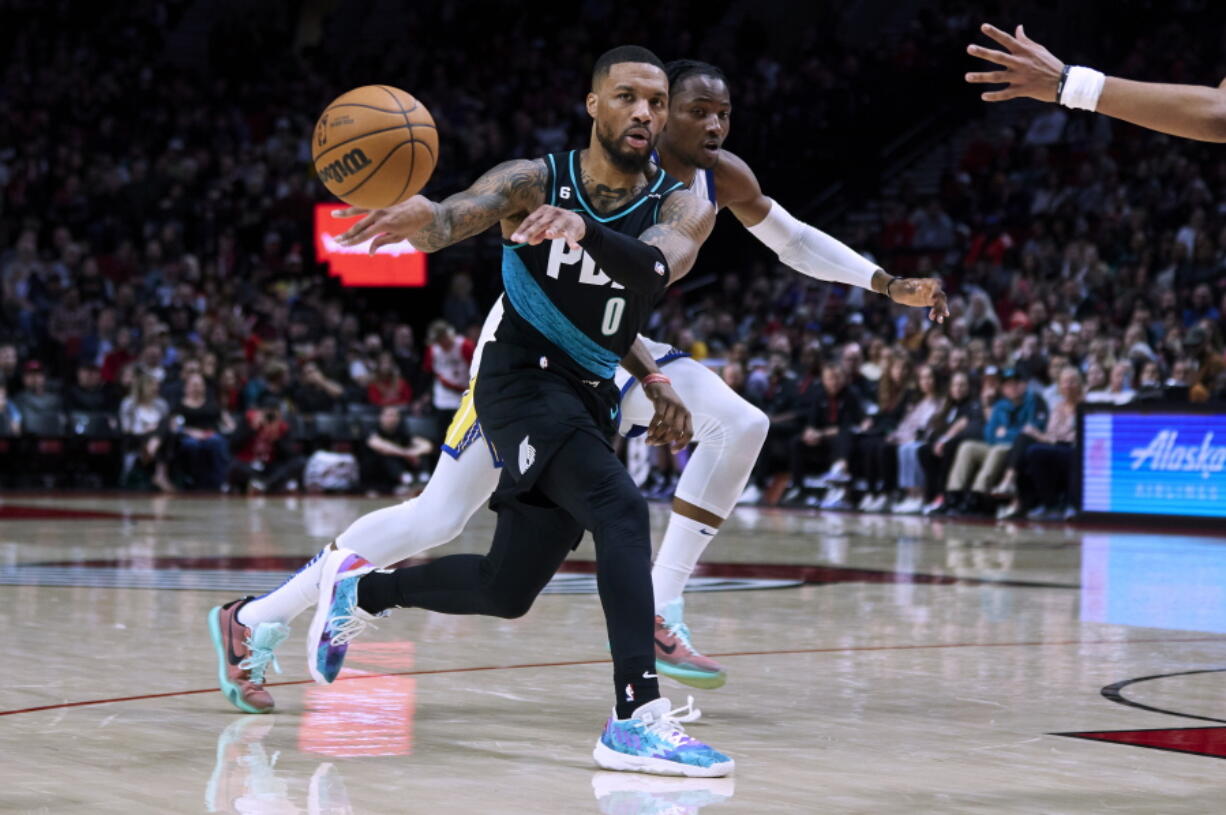 Portland Trail Blazers guard Damian Lillard (0) passes the ball away from Golden State Warriors forward Jonathan Kuminga during the second half of an NBA basketball game in Portland, Ore., Wednesday, Feb. 8, 2023.