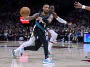 Portland Trail Blazers guard Damian Lillard (0) passes the ball away from Golden State Warriors forward Jonathan Kuminga during the second half of an NBA basketball game in Portland, Ore., Wednesday, Feb. 8, 2023.